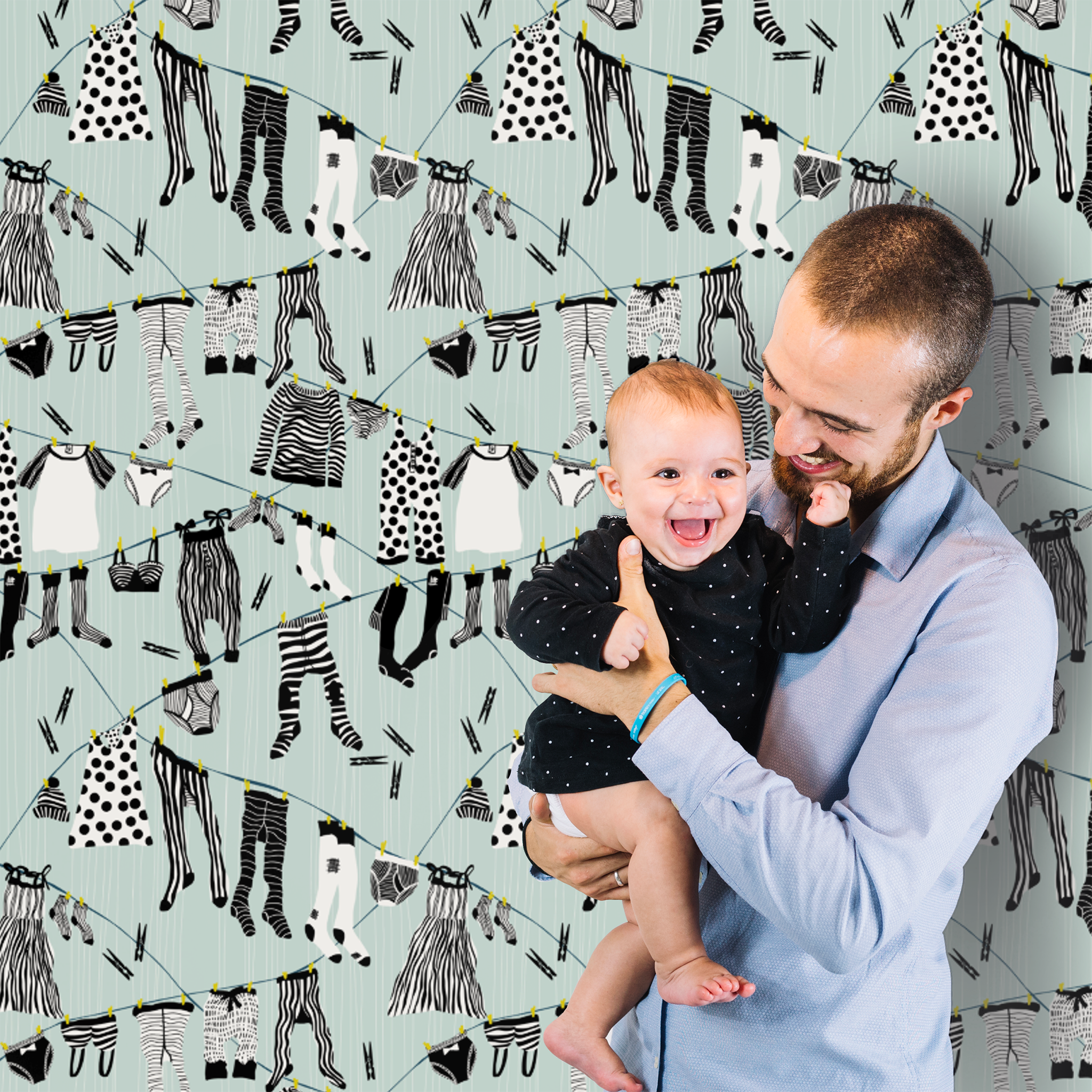 Man holding a baby with a patterned background of black and white clothing illustrations.